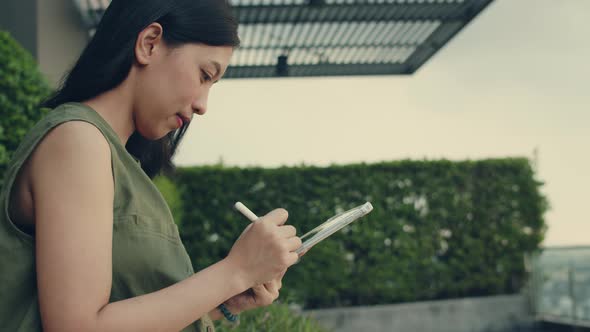 Asian woman using tablet searching on the internet and working online.