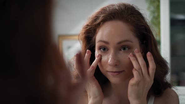 Woman applying eyes cream in the bathroom. Shot with RED helium camera in 4K. alt