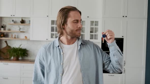 A Male Realtor Showing the Key and Looking at a Camera with a Smile Attracting Customers with a Good alt