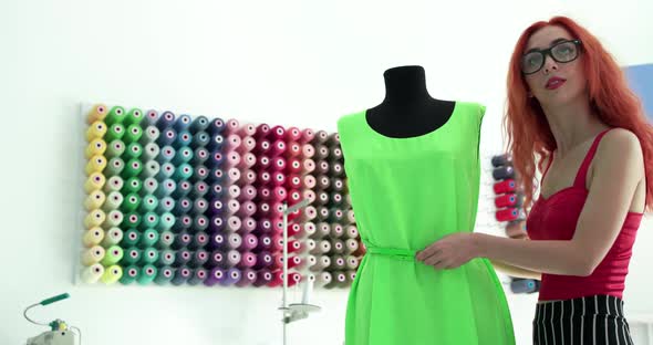 Joyful Tailor Corrects a Belt on Dress and Checks at Mirror It with Smile alt