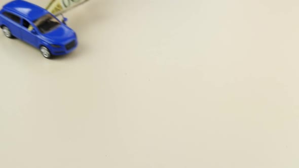 A Small Model of a Toy Car with a Banknote Slowly Rides on the Table. The Concept of Buying Cars alt