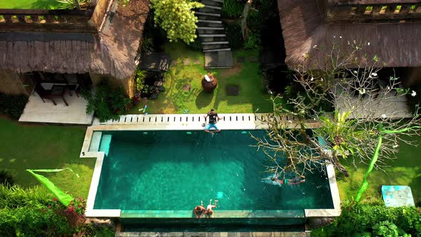 Happy Family Swims and Relaxes in a Luxurious Infinity Pool in a Tropical Paradise in Ubud, Bali alt