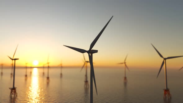 Offshore wind turbines spinning around at the sun setting marine background.