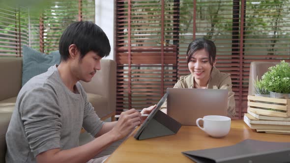 husband and wife discussing paper bill receipt from tablet laptop together on the floor