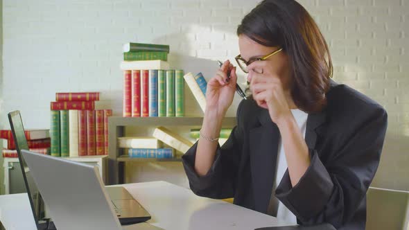 Middleaged Businesswoman Puts on Glasses and Starts Working on a Computer in the Office alt