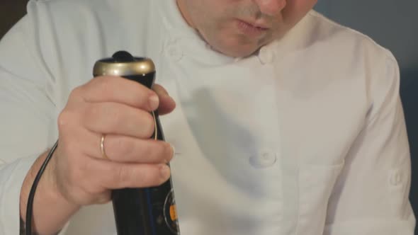 Caucasian Male Pastry Chef Works with a Blender Whips Cream Into a Meringue Roll