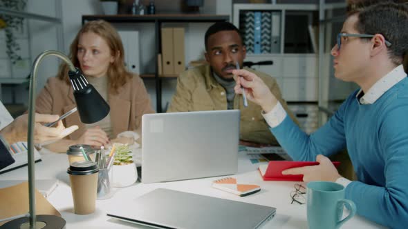 Diverse Group of Businesspeople Discussing Ideas Working in Dark Office at Night alt