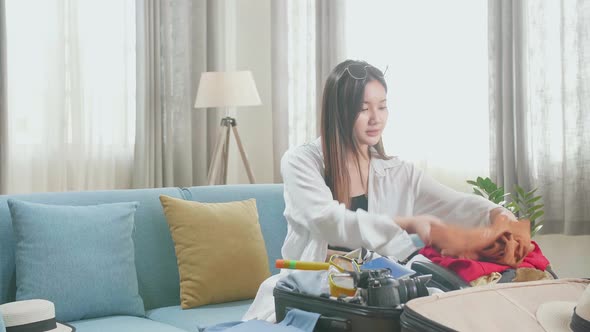 Asian Young Woman Packing Clothes In Suitcase At Home, Preparing For Vacation alt