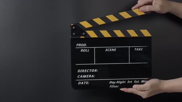 Movie slate or clapperboard hitting. Close up hand holding empty film slate and clapping it on black