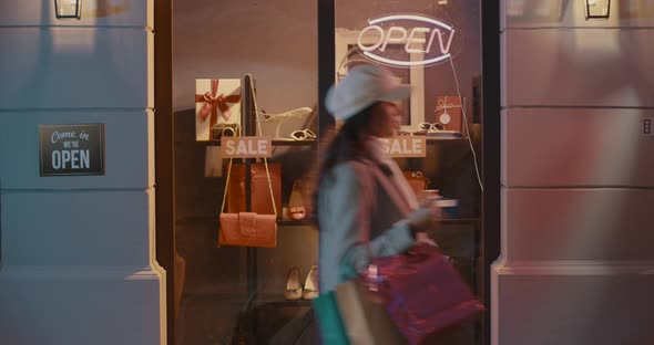 Woman carrying shopping bags and looking at the store window, holidays shopping concept