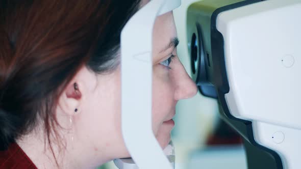 A Lady is Looking Into an Eyeschecking Machine alt