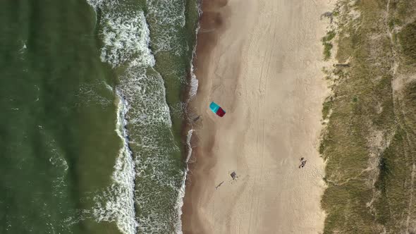 AERIAL: Top View Shot of Isolated Surfer with Wind Kite Waiting on Beach in Nida