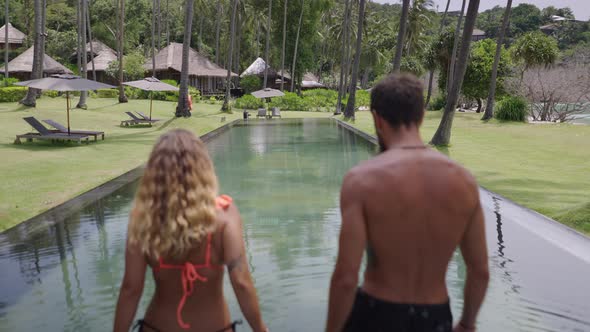 A Backside View of a Couple Got Into a Crystal Clear Pool and Started Swimming alt