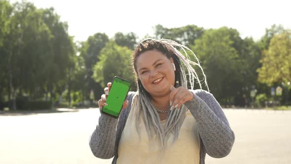 Beautiful Stout Girl with Chromakey on Her Smartphone Advertising Mobile App. Young Pretty Fat Woman alt