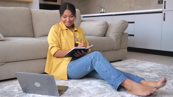 Calm AfricanAmerican Woman Sits on the Floor in Cozy Living Room with a Laptop