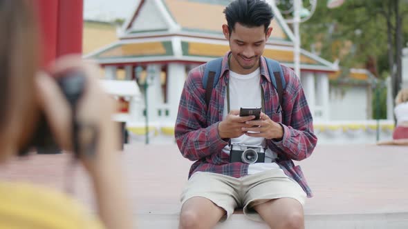 Tourists are Asian man using smartphones checking social media while sitting on the street.