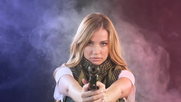 Armed Blonde Woman Shoots with Gun at a Target in the Darkness with Smoke Clouds, Slow Motion alt