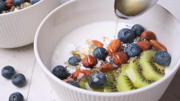 Cooking breakfast cottage cheese with berries, kiwi, nuts and chia seeds. alt