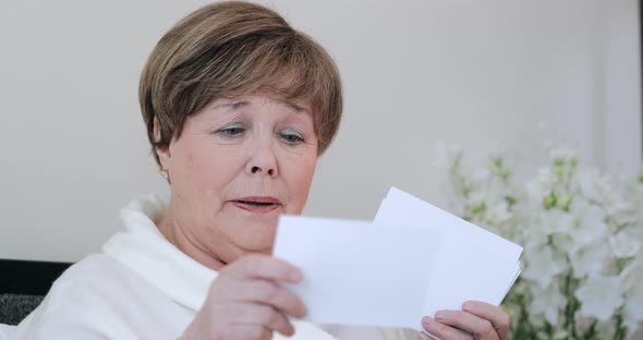 Close Up View of Emotional Grandmother Looking at Photos . Good Looking Elderly Woman in 60s Having alt