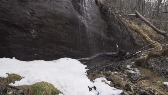 Water coming down onto snow and ice on a waterfall formed by melting snow alt