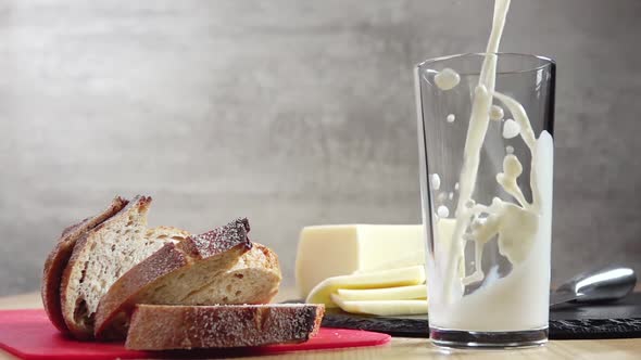 Milk is Poured Into a Glass and Bread and Cheese