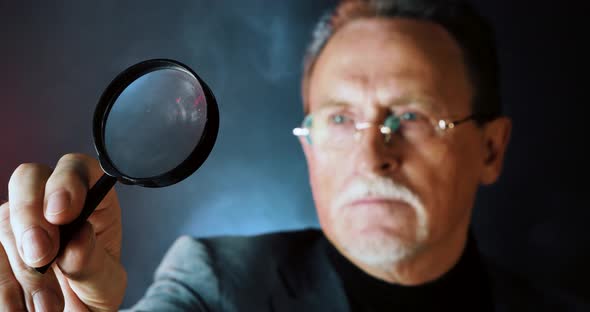 Enlarged Eye Of Mature Tax Inspector Looking Through Magnifying Glass