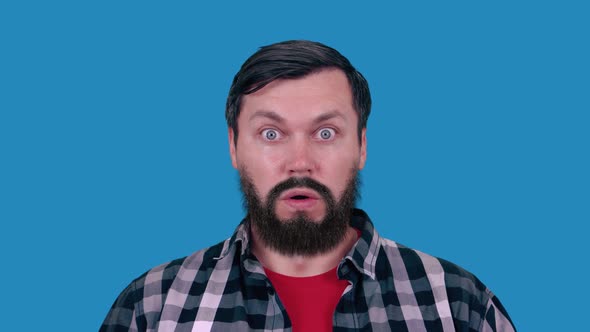 A funny man with a big beard looks into the camera