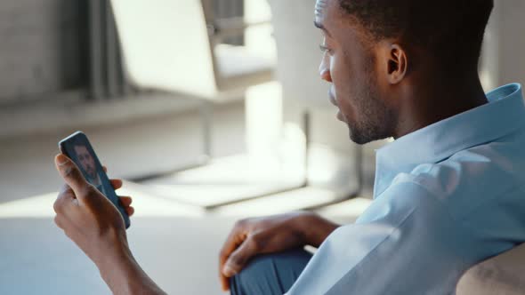 Young man in a shirt making video conference with boss on smartphone alt
