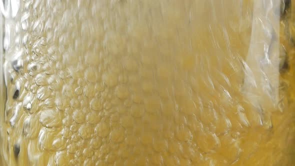 Close up of air bubbles created by someone blowing with straw into full glass of beer or soda alt