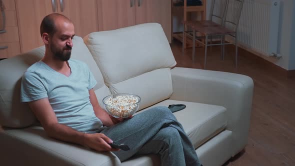 Concentrated Man Sitting in Front of Television Using Control Remote alt