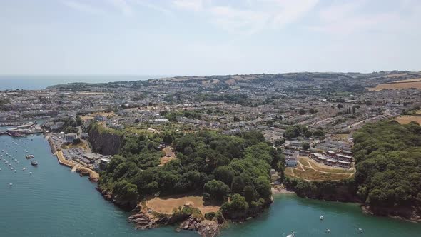 Flying over the coast of Brixham, England. Sky view of cove area on beach. alt