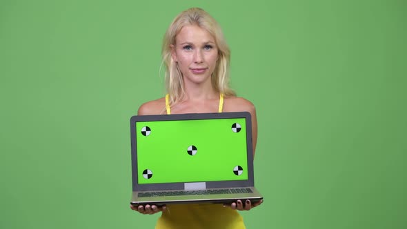 Young Happy Beautiful Blonde Woman Showing Laptop Against Green Background