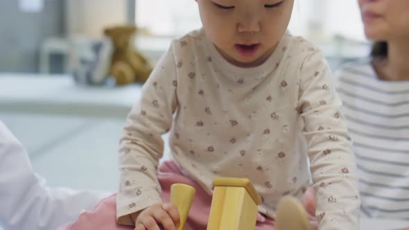 Asian Toddler Girl Playing with Toys while Visiting Clinic alt