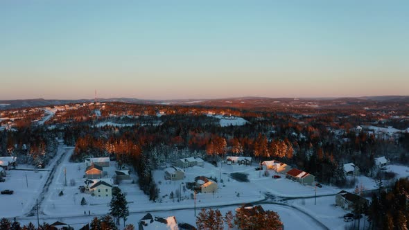 Scenic sunset aerial flying over a snowy residential subdivision on a cold, winter evening. alt