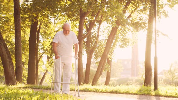 Disabled old man is walking with a walker. Handicapped patient in the park. alt