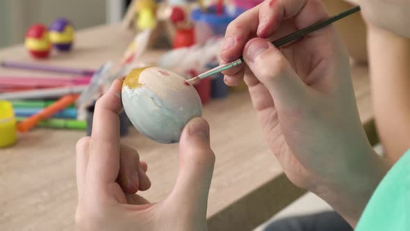 Closeup of a Girl Hands Painting an Easter Egg with Paint and a Brush