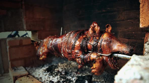 Serbian "Pecenje" roasted pig on a skewer turning over hot ash for an Orthodox event called "slava"