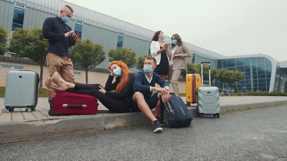 A Group of Tourists in Medical Masks Near the Airport Terminal Is Waiting for the Flight. A Group of alt