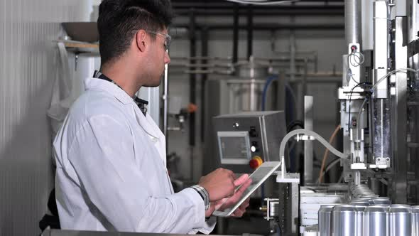 Factory Worker Inspecting Production Line on Beverage Factory with Computer Tablet alt
