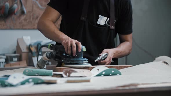 Man Worker Grinding a Wooden Piece in the Workshop Using an Instrument alt