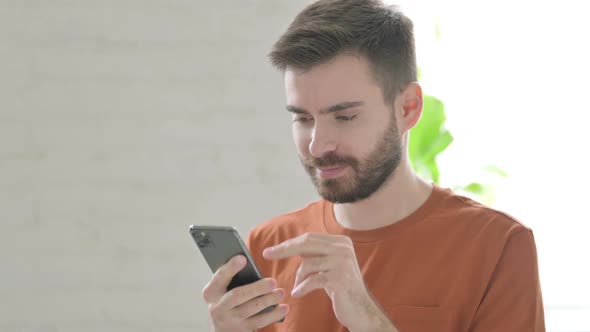 Young Man Browsing Internet on Smartphone alt