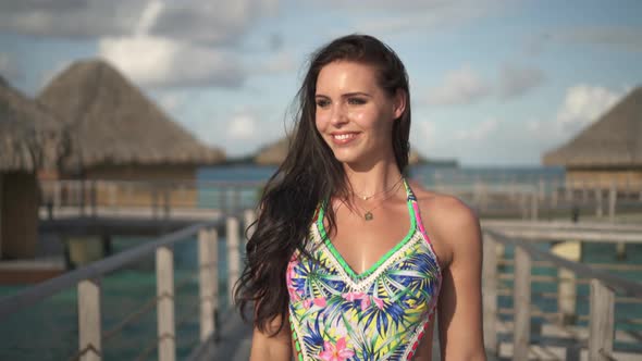 A woman in a bathing suit walking between the overwater bungalows in Bora Bora tropical island alt
