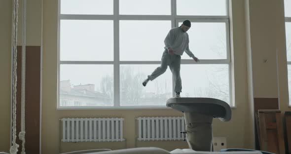 Athlete Man Performs a Gym Flip Jump Back with a Raise in Sportswear - Slow Motion alt