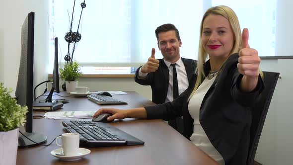 Two Office Workers, Man and Woman, Work on Computers and Show Thumbs up To the Camera alt