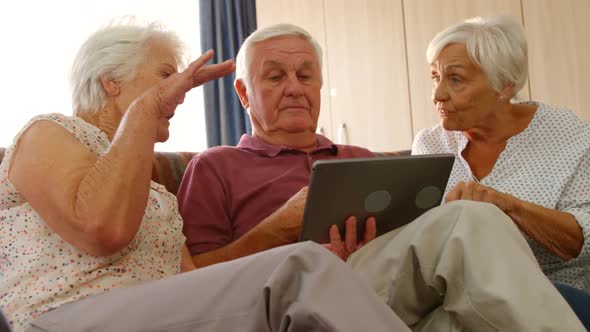 Senior friends discussing together with a digital tablet alt