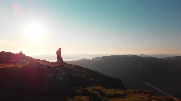 Man walking at the end of a cliff, photographing the beautiful landscape - Aerial 4K alt