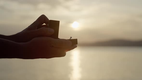 Closeup of Guys Opening a Box with a Hoop By the Sea at Sunset alt