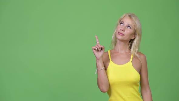 Young Happy Beautiful Blonde Woman Thinking While Pointing Up