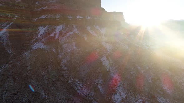 Flying towards cliff as sun rises and disappears behind mountain alt