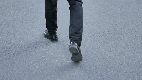 Back View of Walking Feet of Businessman in Suit alt